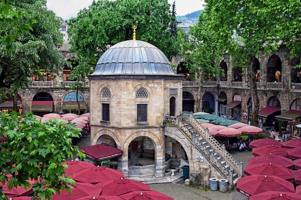 Koza Han'ın ağaçlı avlusu, ortasındaki kubbeli mescit ve çevresindeki revaklar
