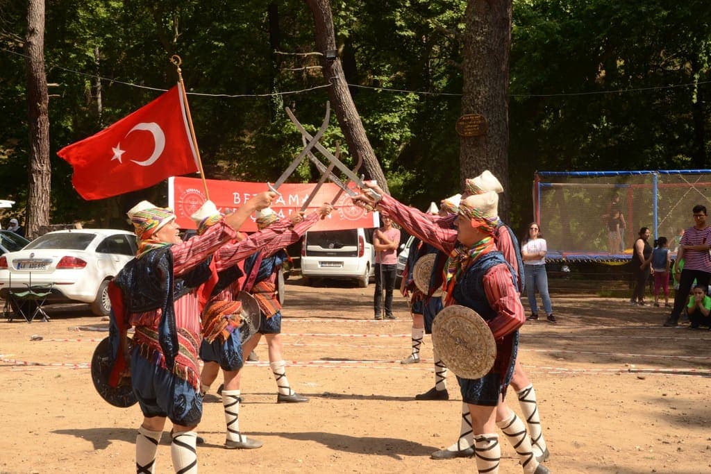 Açık havada geleneksel giysileriyle karşılıklı kılıç kalkan oyunu oynayan ekip