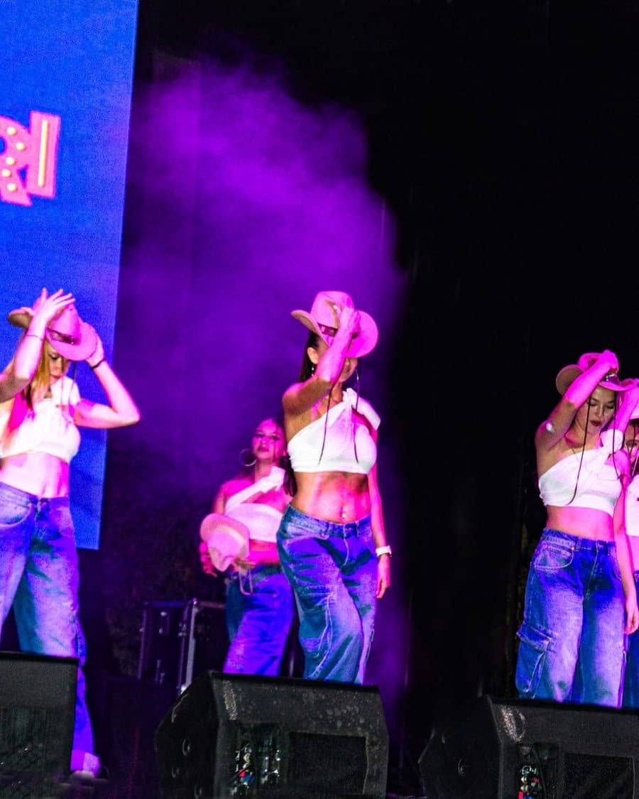Sahnede kırmızı ışık altında salsa figürü yapan dansçı çift