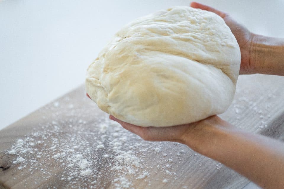 İki avuç arasında tutulan, kabarmış yumuşak ekmek hamuru