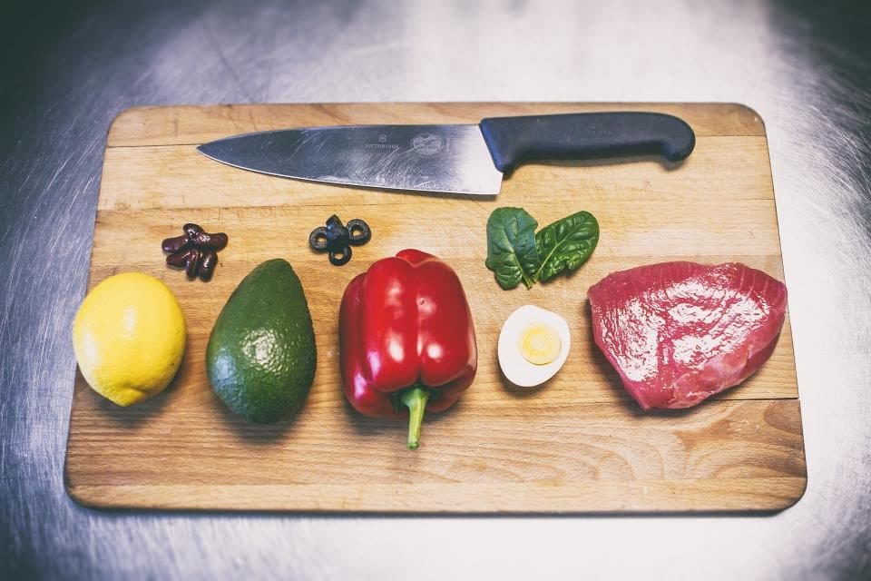 Kesme tahtasında bir şef bıçağı ile yanında limon, avokado ve biber
