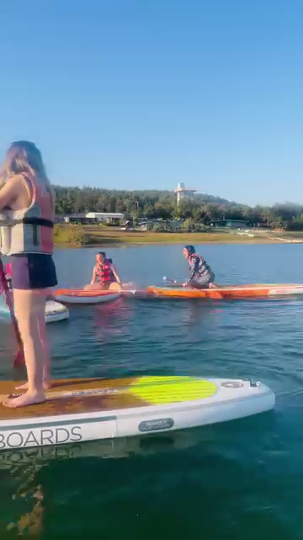 Gölde iki ayrı stand up paddle tahtasında ilerleyen iki kişi