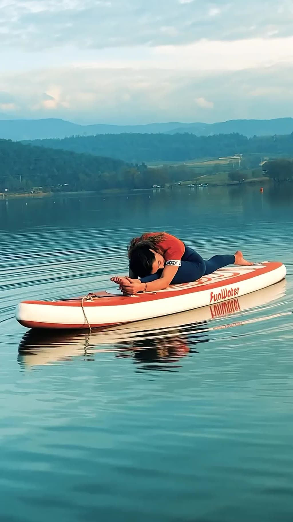 Su üstündeki tahtada SUP yoga duruşu yapan kişi